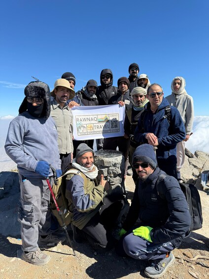 A group of people on a mountain with a banner reading 'RAWNAQ TRAVEL'. 4