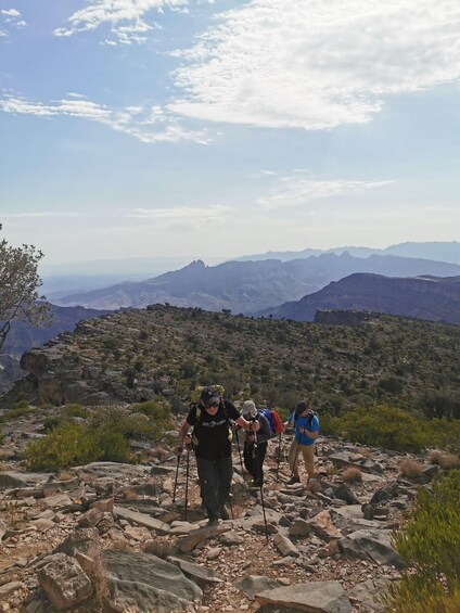 Hikers on a rocky trail with a mountainous landscape in the background. 2