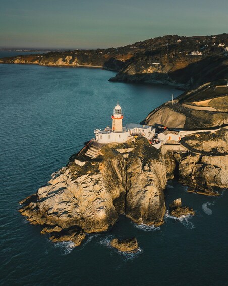 A lighthouse on a rocky cliff by the sea, surrounded by cliffs and a clear sky. 1