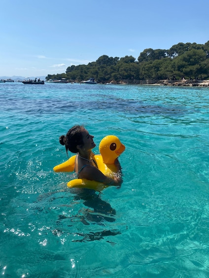 A person in clear water holding a yellow inflatable duck. 3