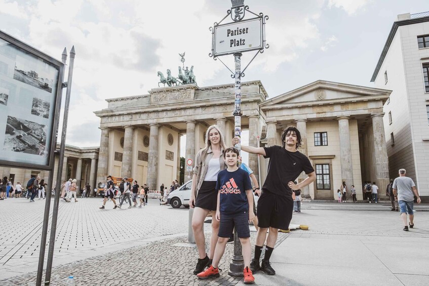 A group of people posing in front of a historical building with a sign reading 'Pariser Platz.' 3