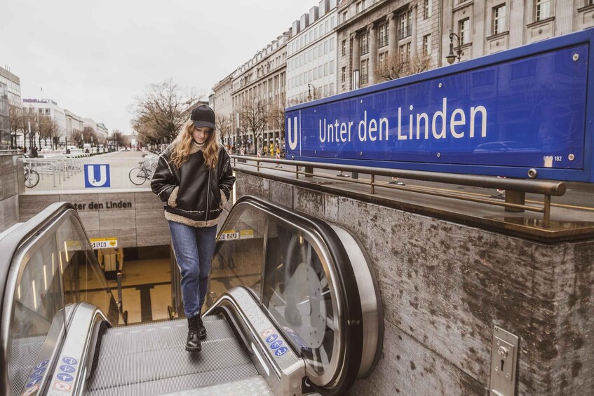 An escalator with a blue sign reading 'Unter den Linden' and a U-shaped sign. 2