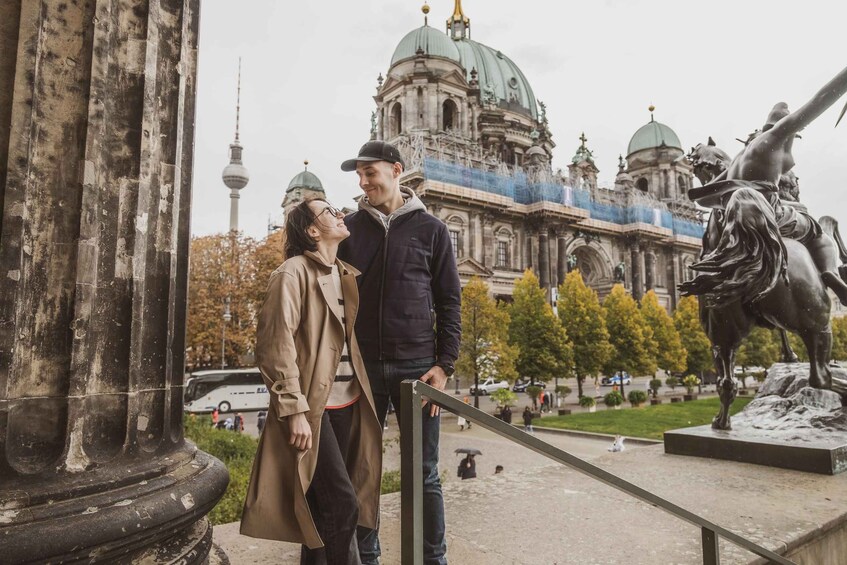A couple standing in front of a historic building with domed architecture and a statue of a horse. 4