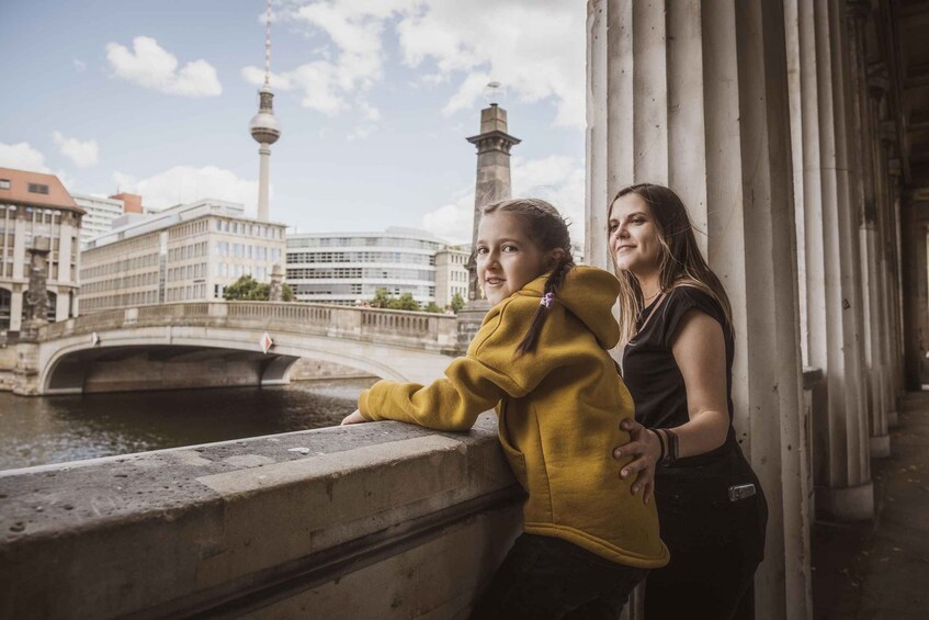 Two people leaning on a bridge railing with a cityscape in the background. 5