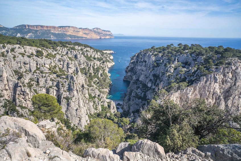 A coastal cliff with a narrow sea passage, rocky terrain, and distant mountains. 1