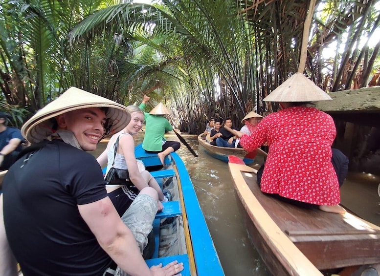People in a boat, wearing conical hats, surrounded by palm trees. 1