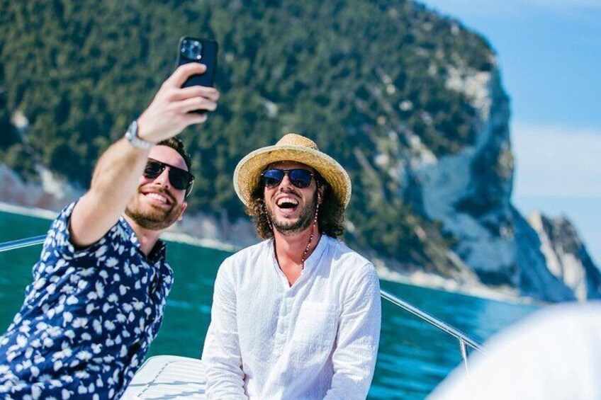 Two people on a boat with a mountainous coastline in the background. 4