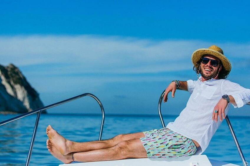A person on a boat with a clear blue sky and a mountainous coastline in the background. 5