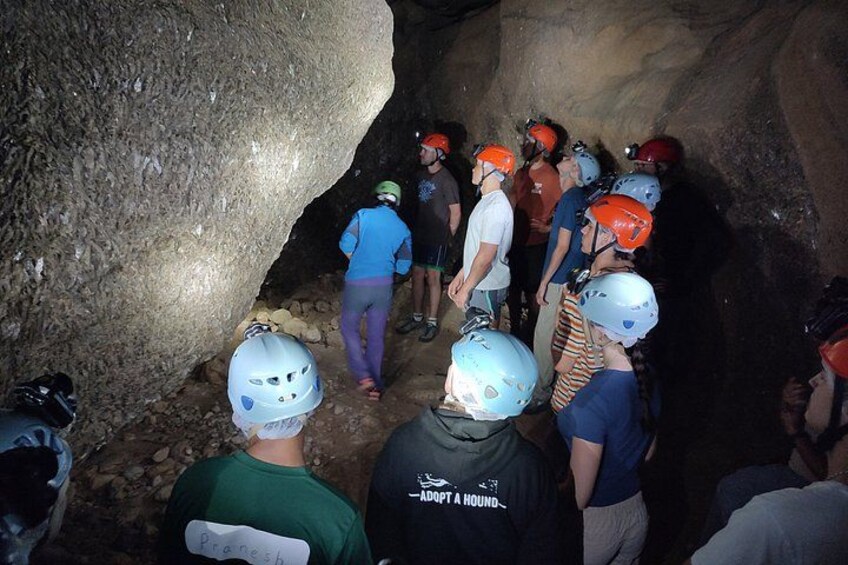 A group of people in helmets inside a cave. 5