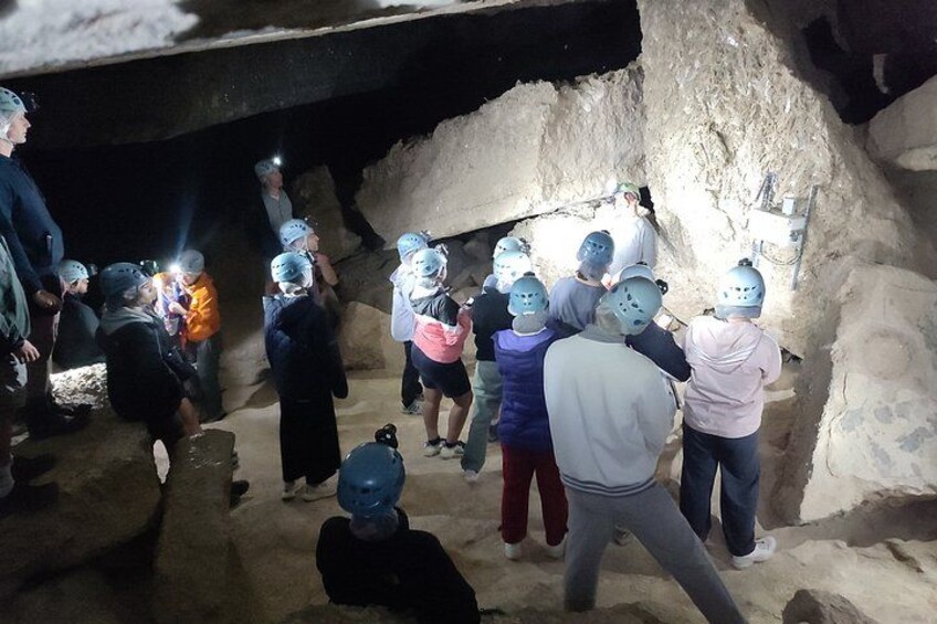 A group of people in a cave with helmets, some holding flashlights. 2