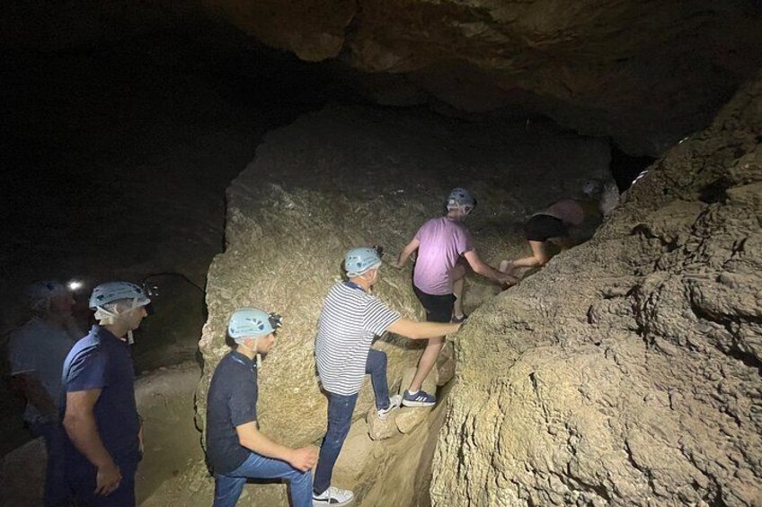 People climbing a rocky cave wall. 3