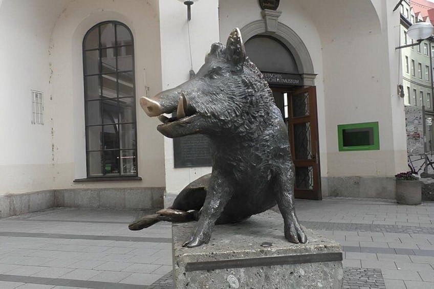 A bronze pig sculpture in a public square with a building in the background. 5