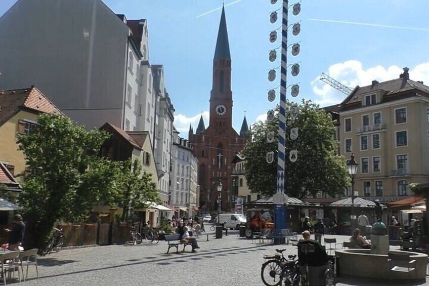 A town square with a clock tower, buildings, and a street with people and bicycles. 4