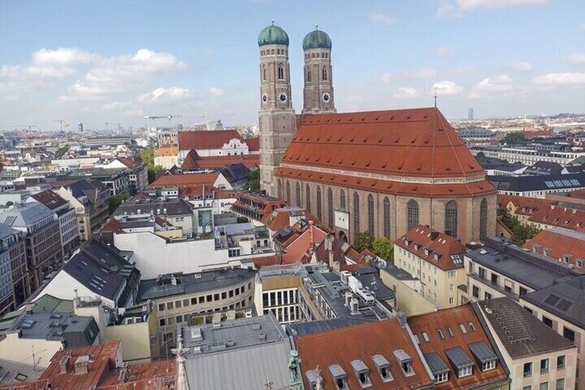 A cityscape with a prominent church featuring two towers and a large building with a red roof. 1