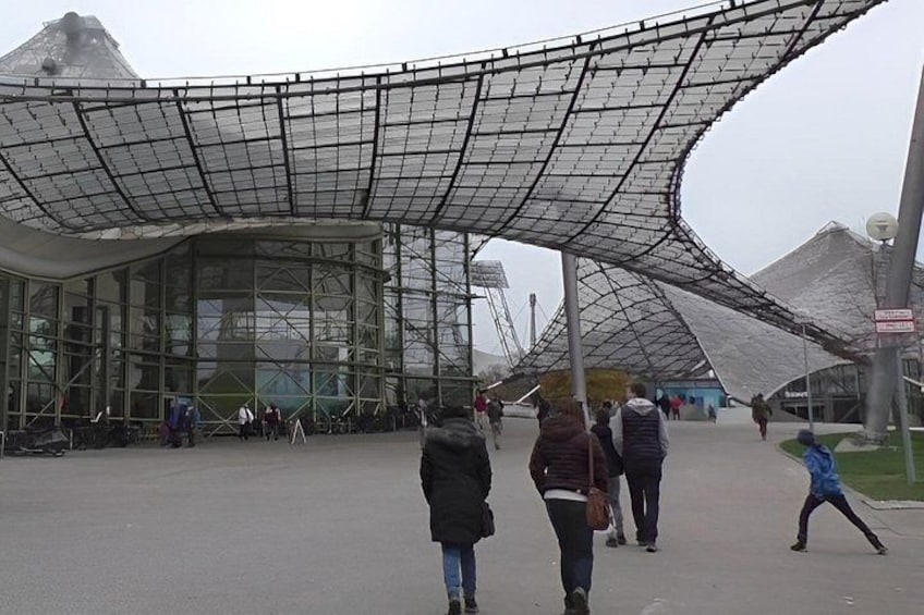 A modern architectural structure with a curved glass facade and a unique roof design. 3