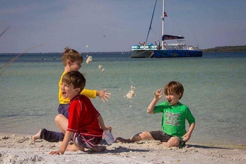 Bambini che giocano su una spiaggia sabbiosa con una barca sullo sfondo. 4