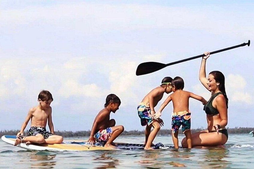Persone su una spiaggia con tavole da surf e una tavola da paddleboard. 5