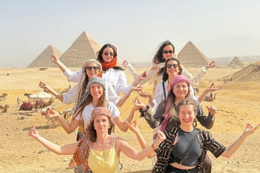 A group of people in a desert with pyramids in the background. 4