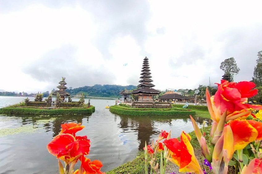 A serene lake with traditional pagodas, vibrant tulips, and a cloudy sky. 2
