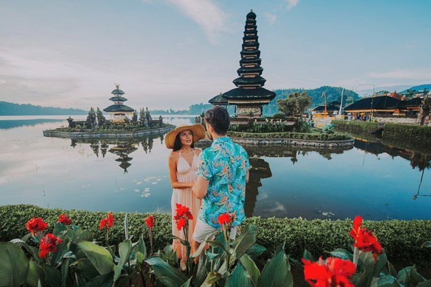 A couple standing by a pond with a pagoda and lotus flowers in the foreground. 1