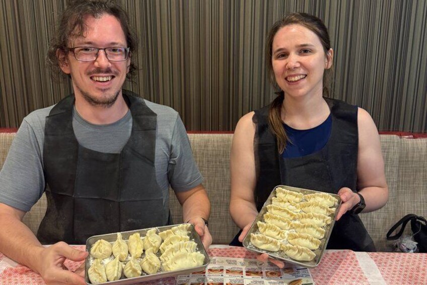 Two people holding trays of dumplings. 2