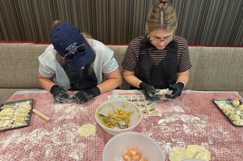 Two people preparing food at a table covered with flour. 5