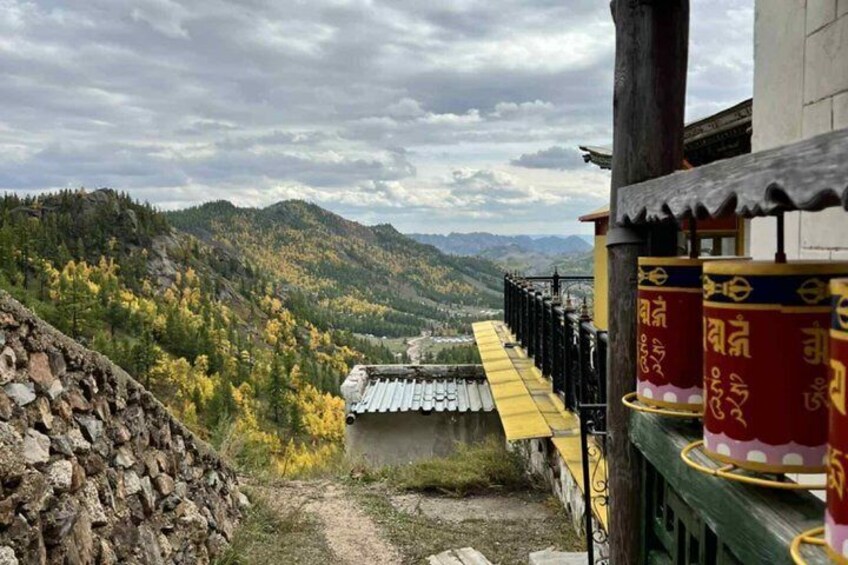 A mountainous landscape with a traditional building and prayer wheels. 5