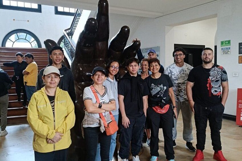 A group of people standing indoors with a large sculpture in the background. 2
