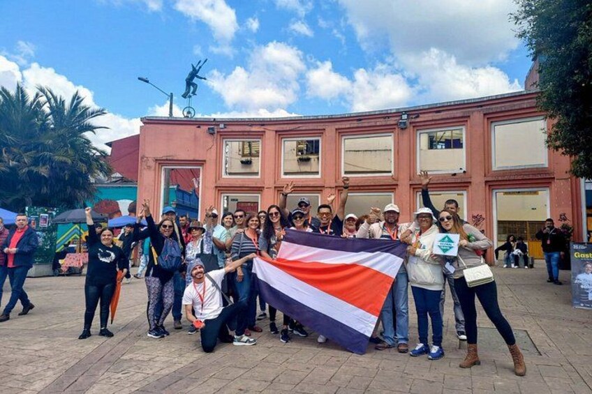 A group of people holding a flag in front of a building with a statue on top. 5