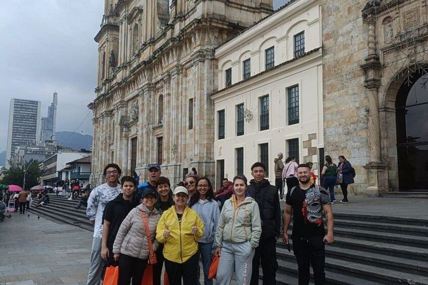 A group of people standing in front of a historic building with large steps and a cityscape in the background. 3