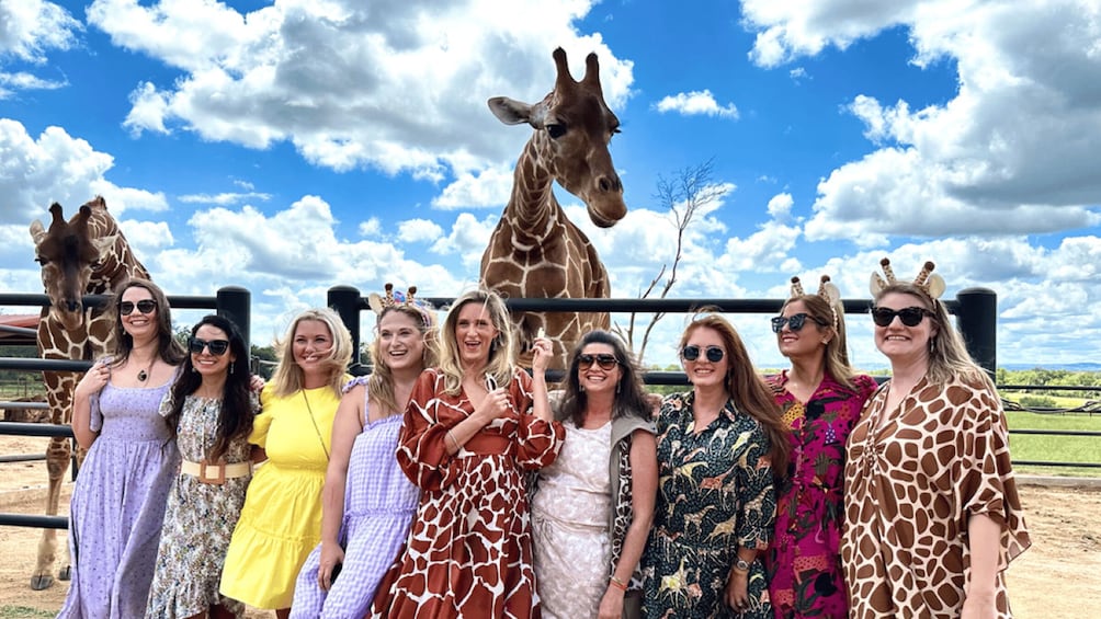A group of people in a giraffe enclosure with giraffes. 1