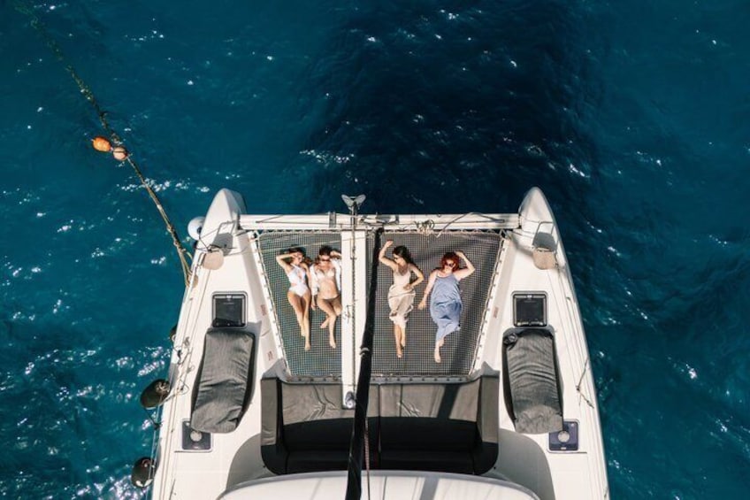 A boat with three people on deck, surrounded by clear blue water. 1