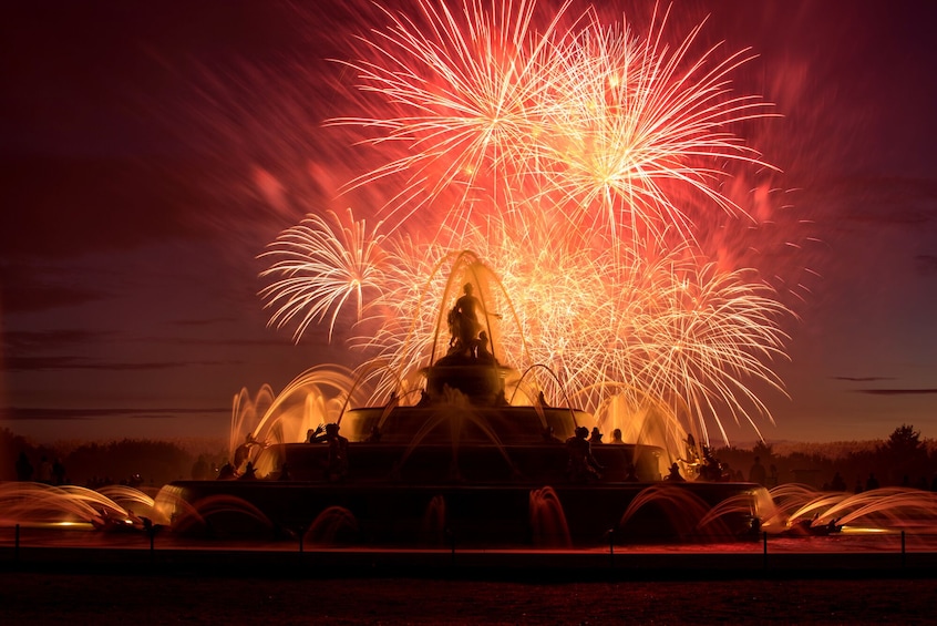 Una fuente con chorros de agua y fuegos artificiales al fondo. 4