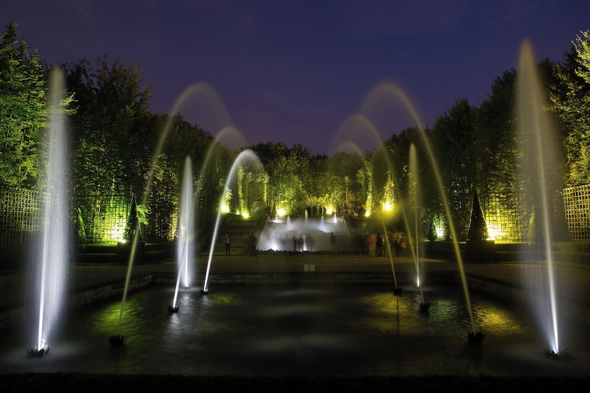 Espectáculo nocturno de una fuente con múltiples chorros de agua iluminados por luces. 5