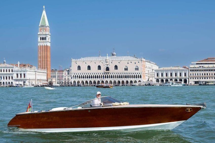 A wooden boat on Venice's Grand Canal with the Doge's Palace and the Campanile di San Marco in the background. 1