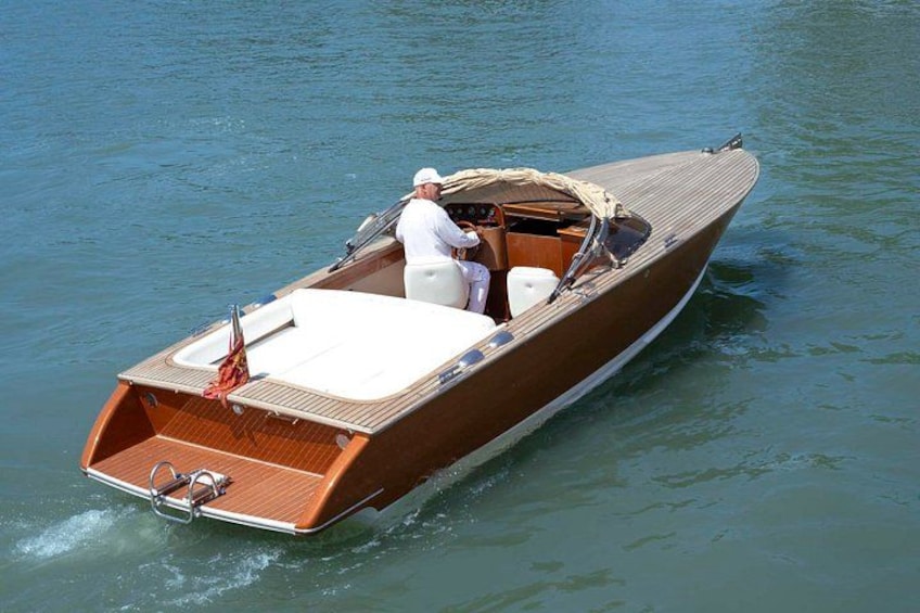 A wooden motorboat with a white interior, moving on calm water. 5