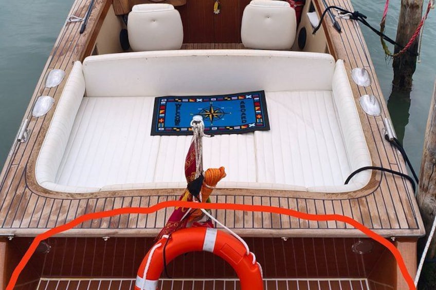 A boat with a white interior, a steering wheel, and a life buoy. 3