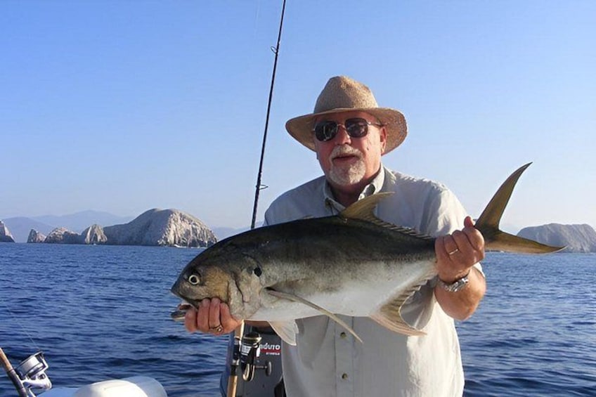 A person holding a large fish on a boat with a clear blue sky and distant landforms in the background. 3