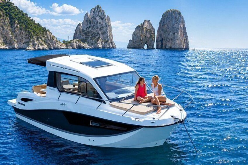 A motorboat on calm waters with two people on deck, surrounded by rocky cliffs and clear skies. 1