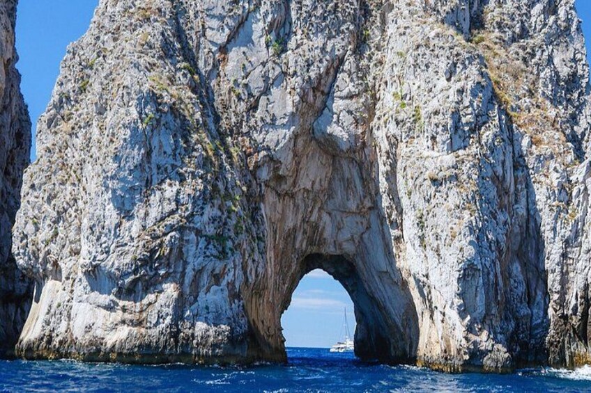 A large rock formation with a natural arch over the sea. 2