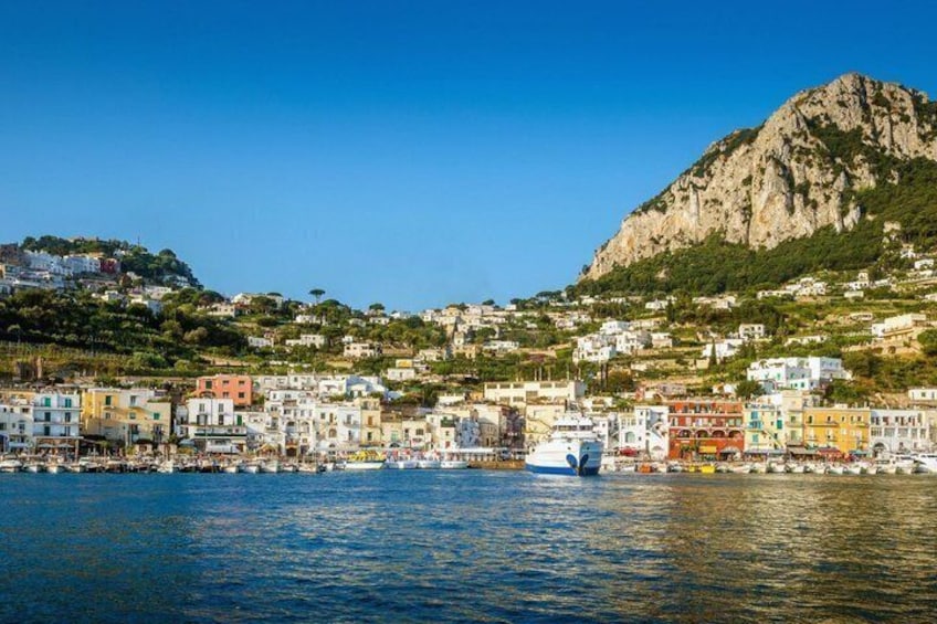 A coastal town with colorful buildings, a mountain, and boats on the water. 3
