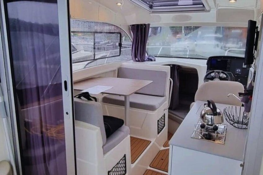 A compact interior with a dining table, cushioned seating, and a small kitchenette. 4