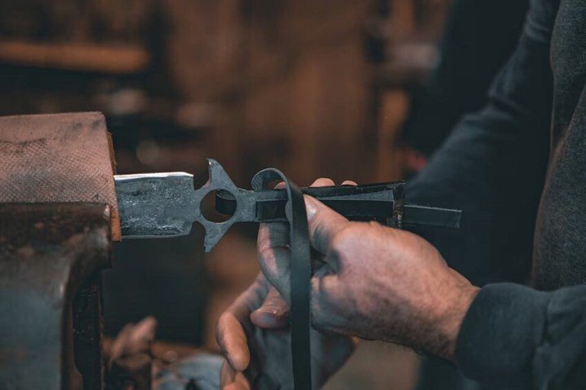A person using a metalworking tool, possibly a press or hammer, on a piece of metal. 2