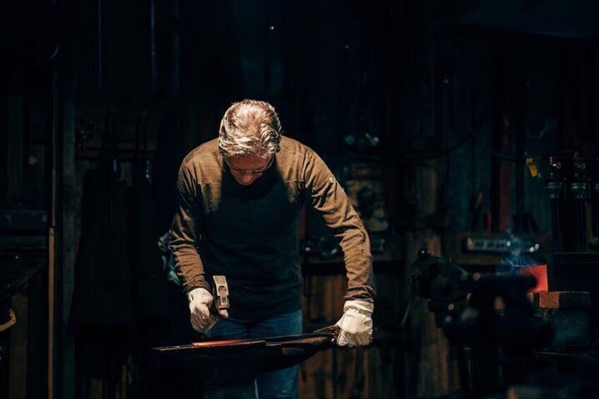 A person working with a hammer in a dimly lit workshop. 4
