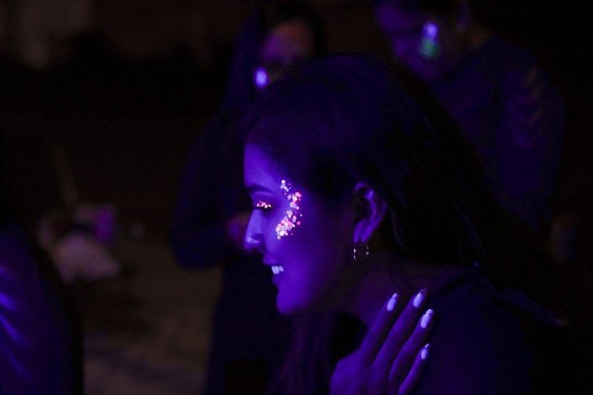 A person with a glowing face, possibly from LED lights, in a dimly lit environment. 5