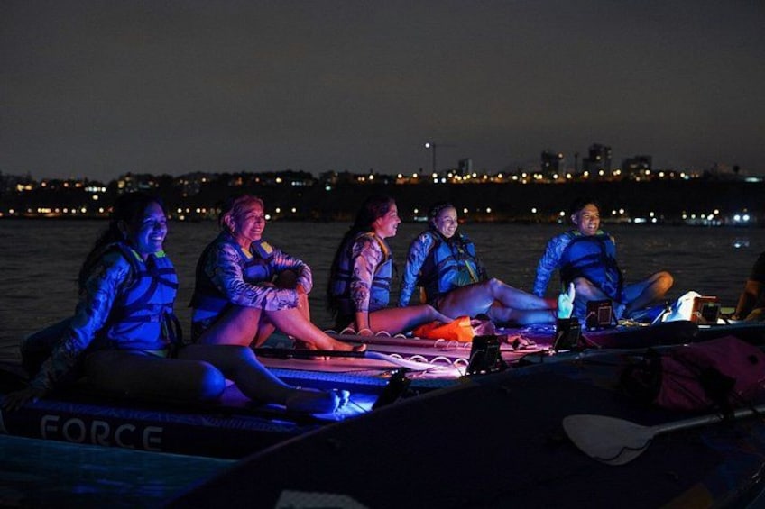 A group of people on a boat at night with city lights in the background. 3