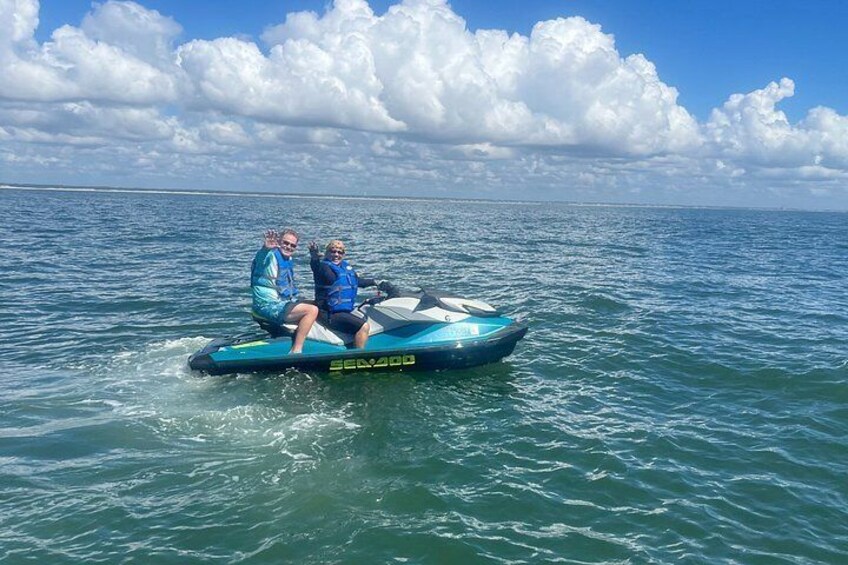 Two people on a jet ski in the ocean with a clear sky and clouds. 2