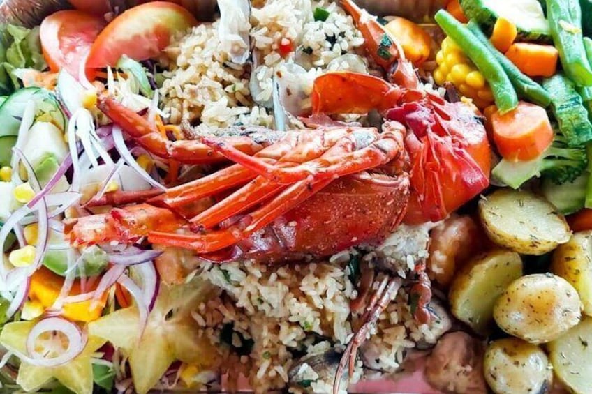 A seafood platter with a lobster, rice, vegetables, and potatoes. 5