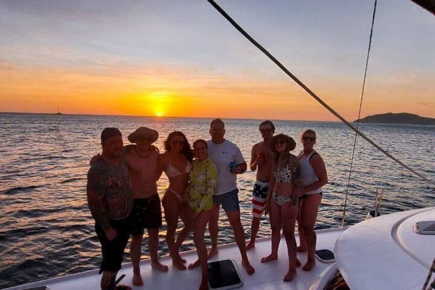 A group of people on a boat at sunset with the sun visible on the horizon. 4