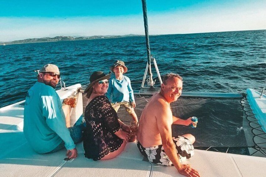 A group of people on a boat with the sea and a distant shoreline in the background. 1